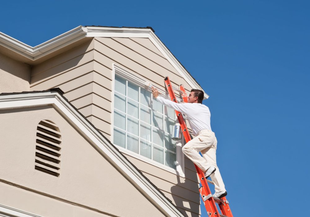 House painter with paint brush painting the trim of a 2nd story window of a Cape Cod Style house.Take a look at our lightbox's of other related images.